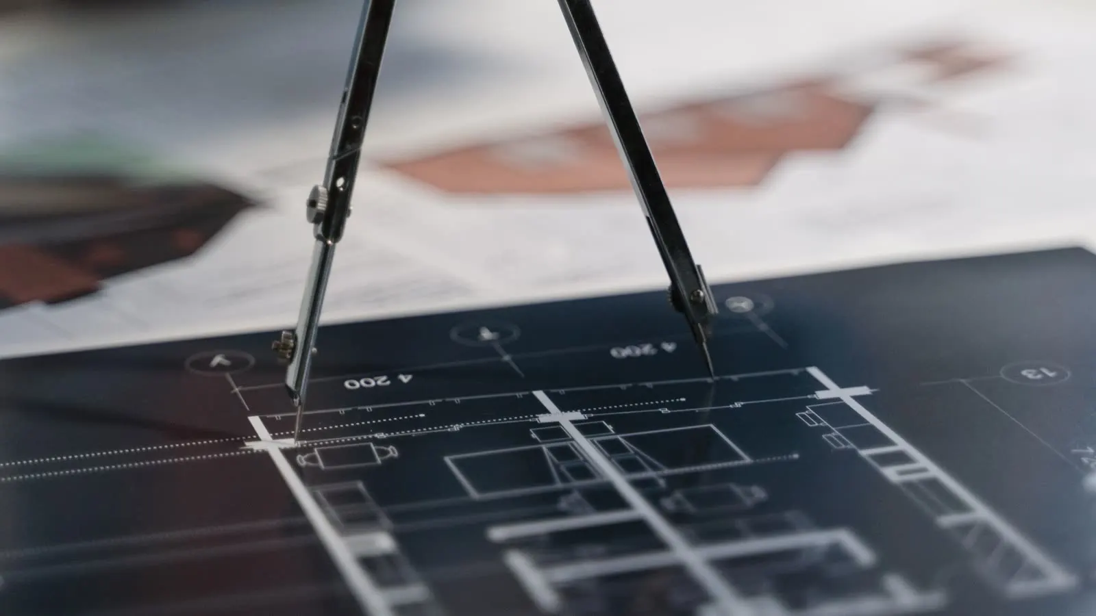 A pair of dividers resting on a technical drawing